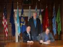 Montana Governor Steve Bullock (seated, right) signs Montana House Bill 148 into law on February 28 as bill sponsor Pat Connell, WA7PDC (seated, left) and ARRL Montana Section Manager-elect George Forsyth, AA7GS (standing) look on. [William Erhardt, K7MT, photo] 